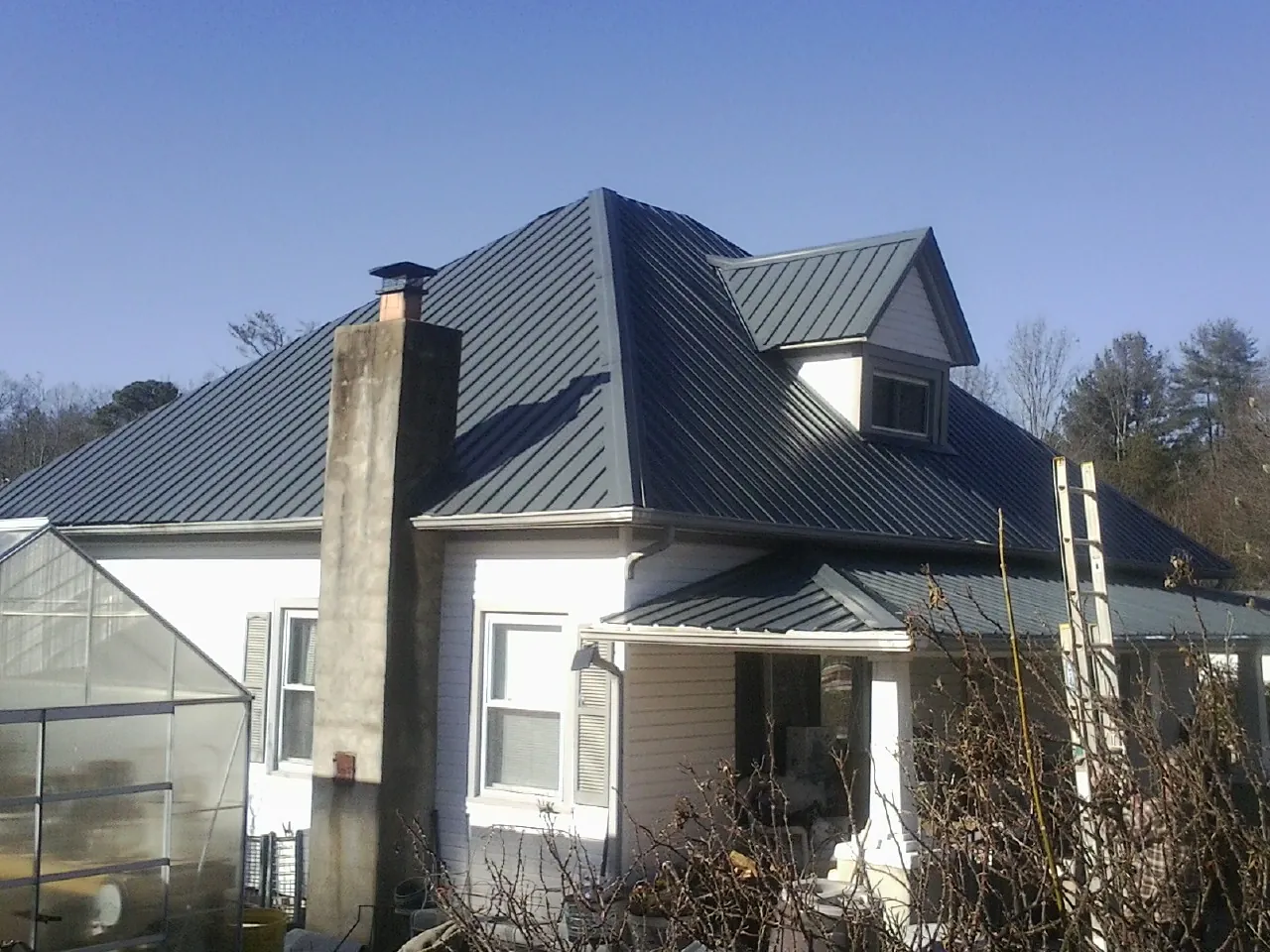 Dark blue standing seam metal roof on a white farmhouse with dormer — Slate & Tile Roof Repair by Roofing Brothers in Oaklyn