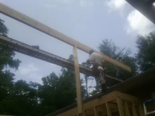 Carpenter setting a ridge beam over a new addition frame — Ice Dam Removal by Roofing Brothers in Oaklyn