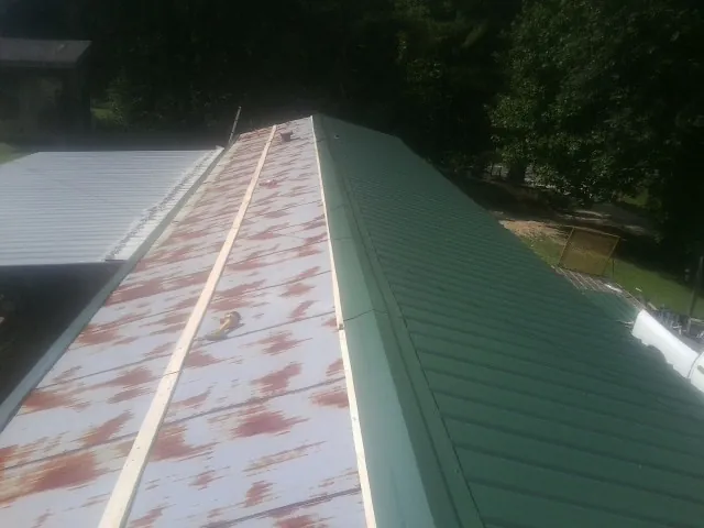 Old rusted panels beside newly installed green metal roofing — Wind Damage Roof Repair by Roofing Brothers in Oaklyn
