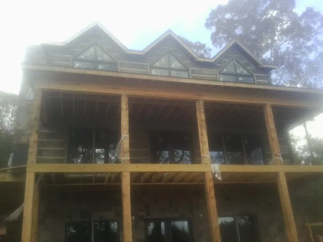 Dormers and porch framing on a large log home under construction — Roof Coating work by our crew in Oaklyn
