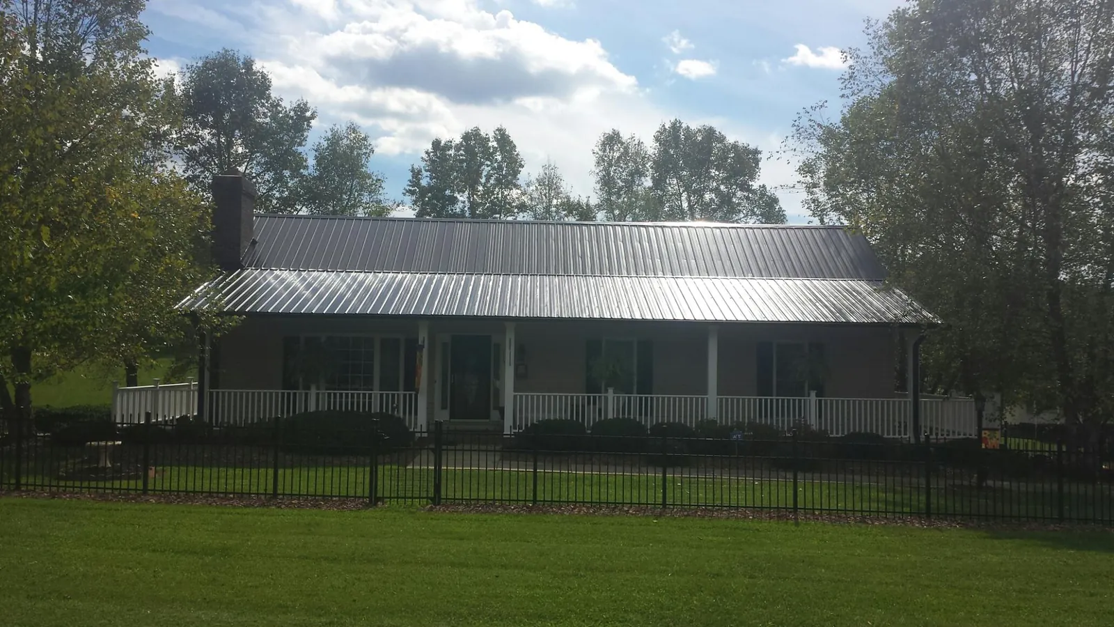 Gray metal roof on a brick ranch with a full width front porch — Gutter Guard Installation work by our crew in Oaklyn