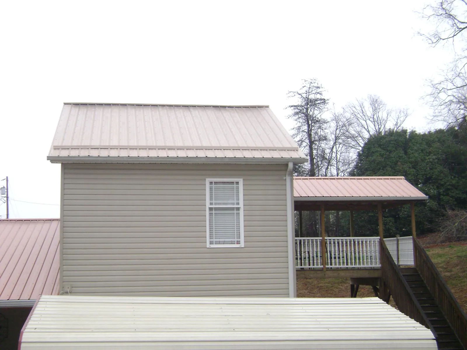 Tan metal roofs on a two story addition and attached porch, from a Roof Replacement job in Oaklyn