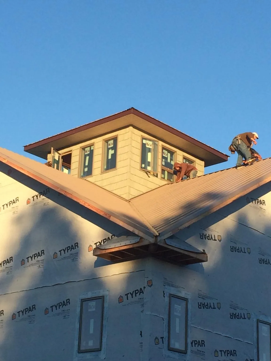 Roofers working around a rooftop cupola on a new metal roof at sunset — Roof Waterproofing in Oaklyn by Roofing Brothers